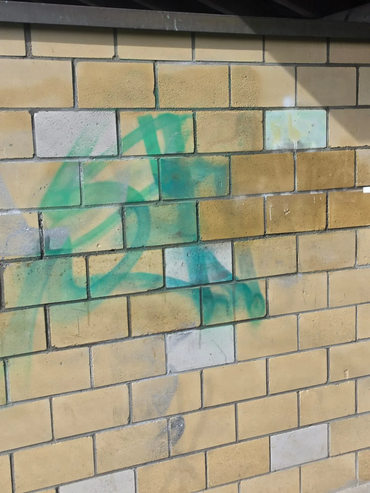 Backsteinwand mit Graffiti vor der Reinigung
